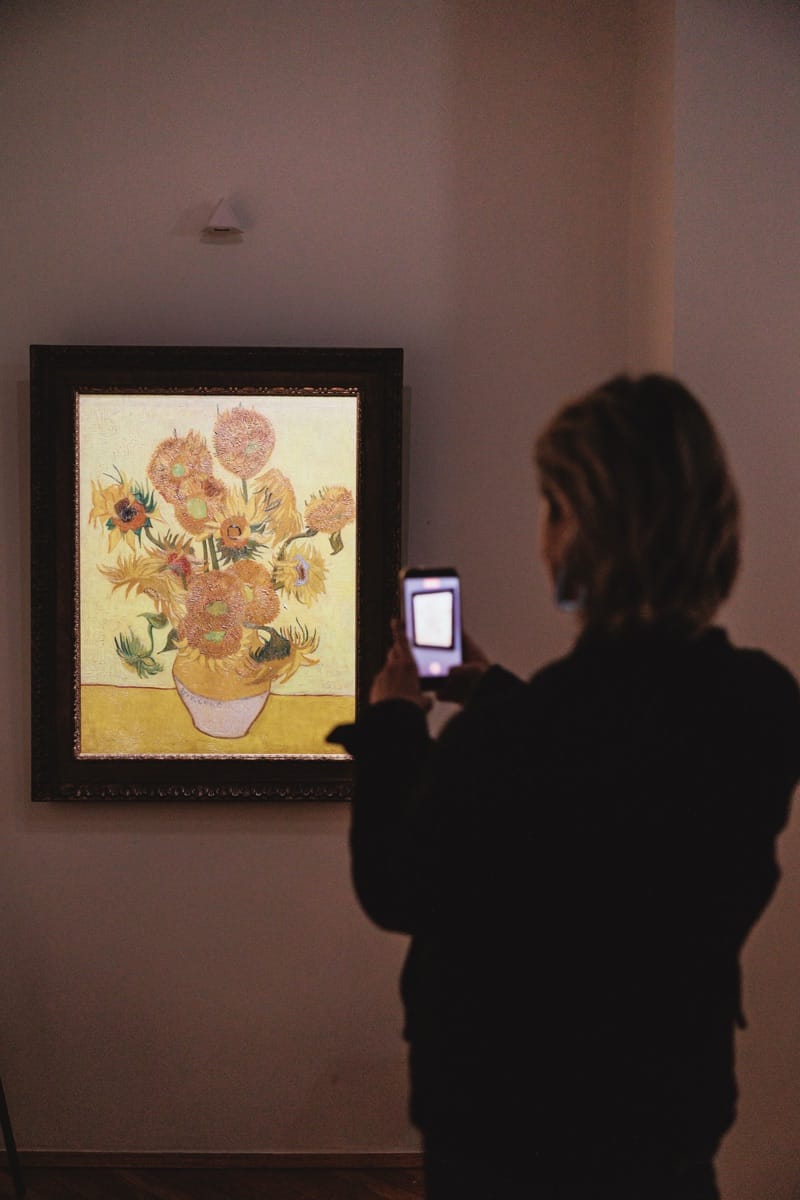 A visitor photographing the Sunflowers Museum Edition reproduction